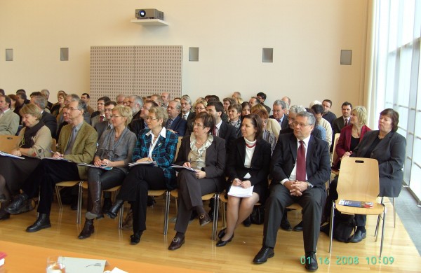 das Publikum sitzt in Sesselreihen im Saal 